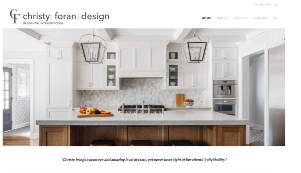 A modern kitchen featuring white cabinetry, a large island with a marble countertop, and stylish pendant lighting. The space is bright and inviting, with fruit displayed on the island and a decorative backsplash.